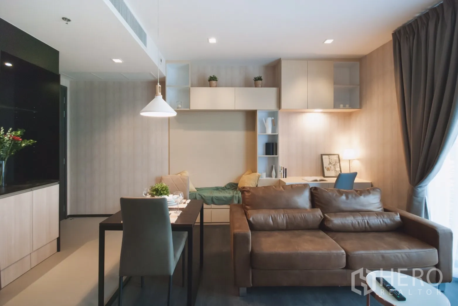 公寓 出租在Watthana, Bangkok - 开放式客餐厅，棕色皮沙发、餐桌与内置书架和书桌。