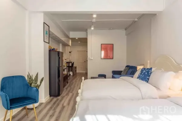 Townhouse for rent in Bang Rak, Bangkok - Spacious bedroom with twin beds, a seating nook, and wood-look floors.