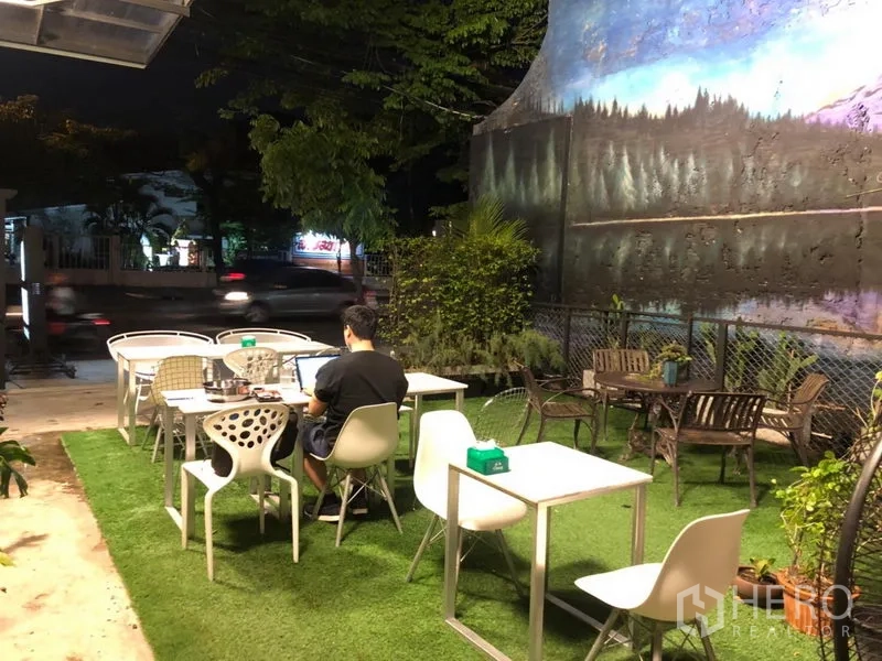 พื้นที่ขายปลีก ให้เช่าในKhlong Toei, Bangkok - มุมที่นั่งกลางแจ้งบนหญ้าเทียม พร้อมโต๊ะสีขาวติดริมถนน