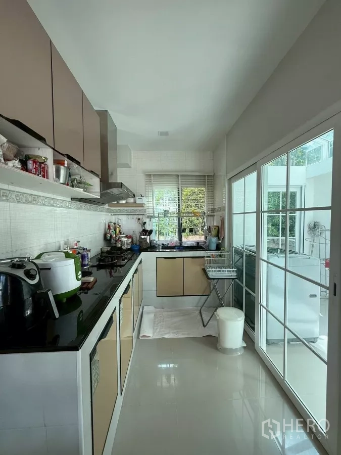 Detached House for rent in Bang Phli, Samut Prakan - Separate Thai kitchen with stove, range hood and long black countertop.