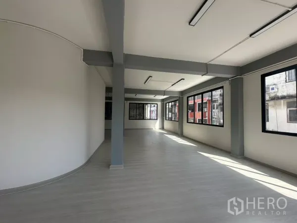 办公空间 出租在Phra Khanong, Bangkok - 狭长型办公大厅，多扇窗与线性顶灯，待进一步装潢。