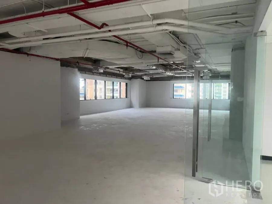 สำนักงาน ให้เช่า - พื้นที่สำนักงานเปิดโล่งมองจากหน้าประตูกระจก เห็นงานระบบเพดานและพื้นคอนกรีต