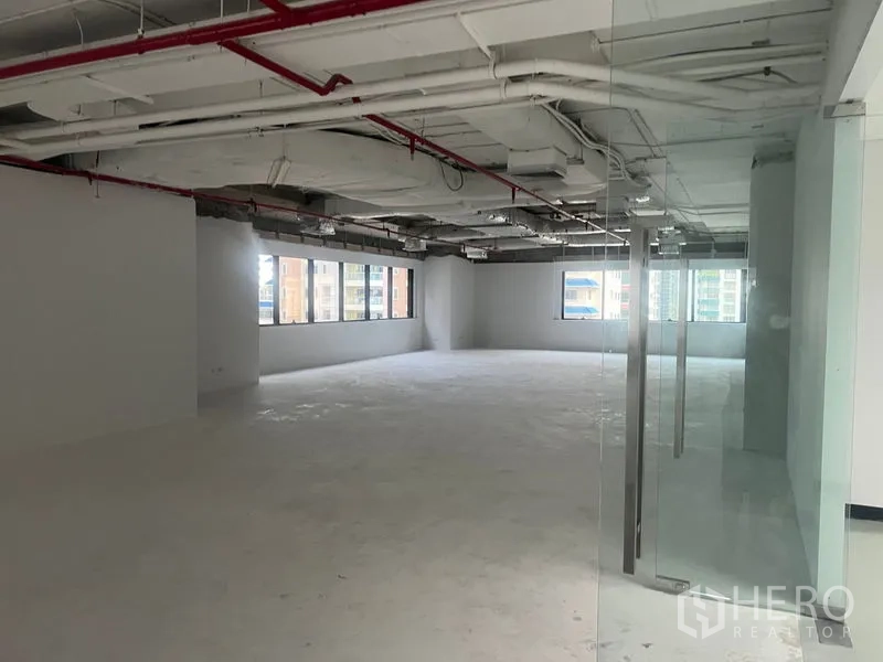 สำนักงาน ให้เช่า - พื้นที่สำนักงานเปิดโล่งมองจากหน้าประตูกระจก เห็นงานระบบเพดานและพื้นคอนกรีต
