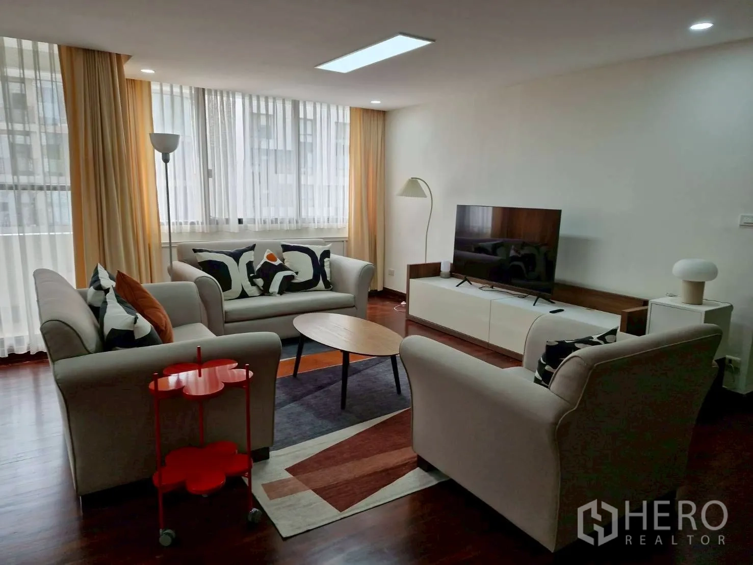 Condominium for rent in Khlong Toei, Bangkok - Another angle of the living room with rug, sofas, floor lamp and wide windows.