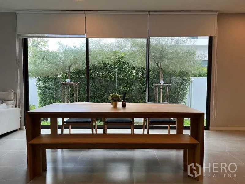 บ้าน ให้เช่าหรือขาย - มุมทานอาหาร โต๊ะไม้ยาวและม้านั่งข้างประตูกระจก มองเห็นแนวต้นไม้