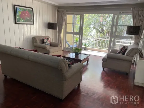 公寓 出租在Watthana, Bangkok - 采光充足的客厅，沙发组合与茶几，推拉门通向绿意阳台。