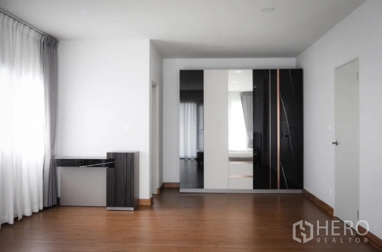 Detached House for rent in Bang Phli, Samut Prakan - Large room with glossy black-and-white wardrobe and wide wood floors.