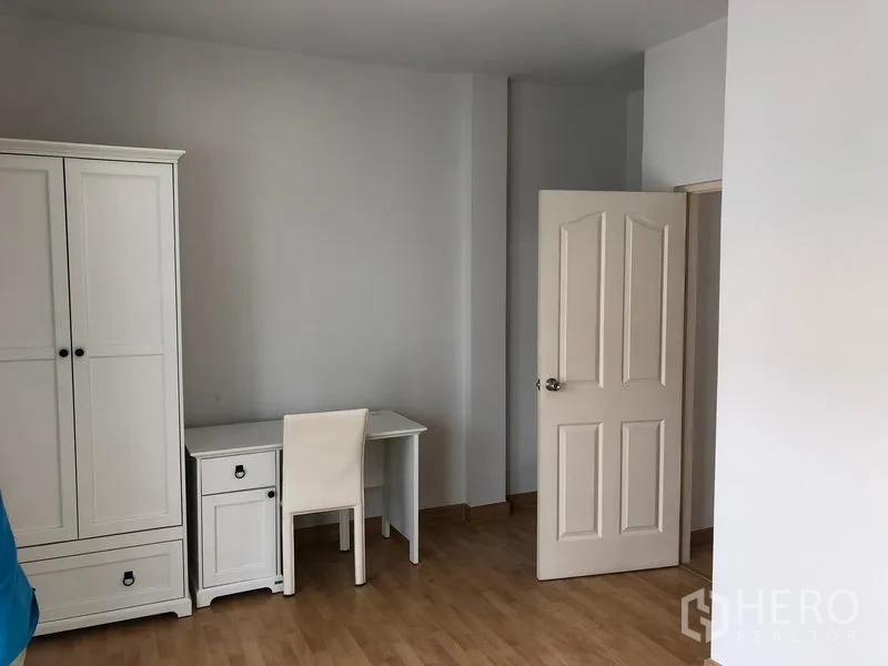 联排别墅 出租或出售在Wang Thonglang, Bangkok - 卧室一角配白色衣柜、书桌与木纹地板。