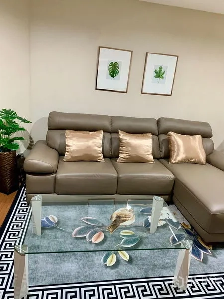 Condominium for rent in Huai Khwang, Bangkok - Modern lounge with L-shaped leather sofa and glass coffee table on a patterned rug.