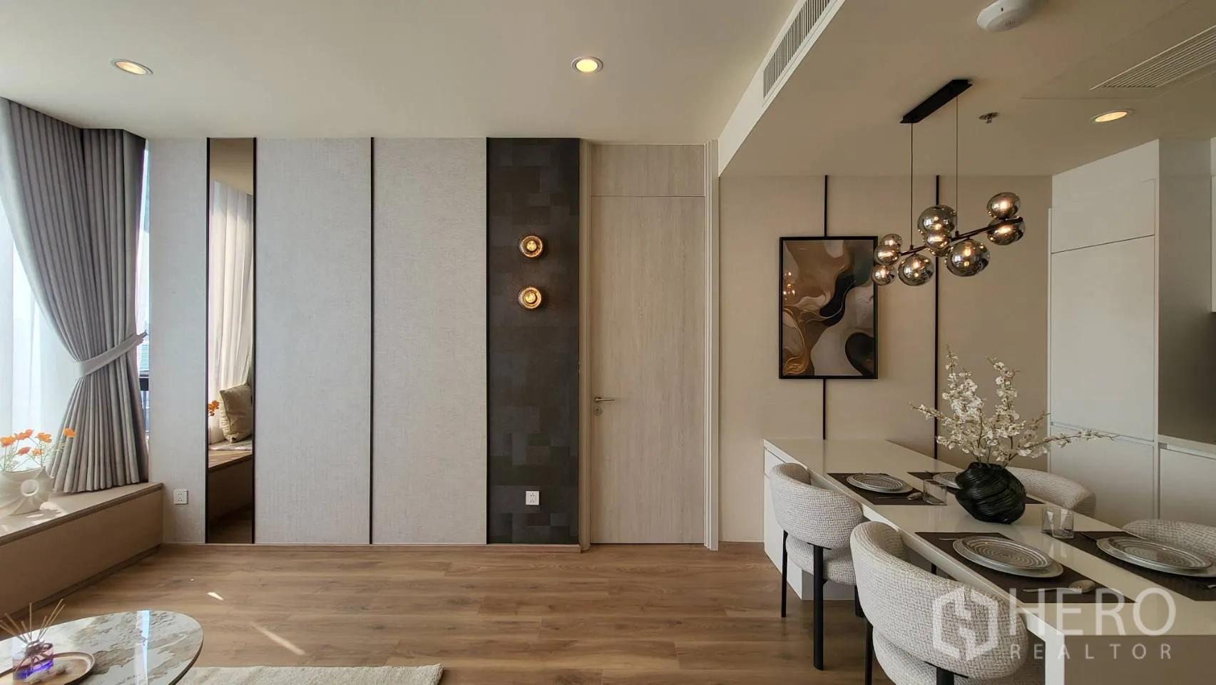 公寓 for sale in Watthana, Bangkok - 明亮客厅，木地板、壁灯、四人餐桌与高挑窗帘。