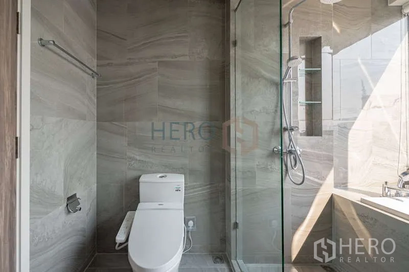 คอนโด ให้เช่า - ห้องน้ำโมเดิร์นพร้อมตู้ชาวเวอร์กระจก โถสุขภัณฑ์ และพื้นที่อ่างอาบน้ำผนังหินสีเทา