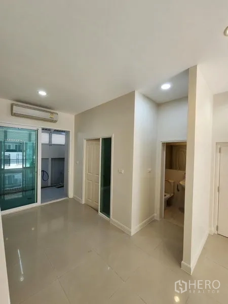 Townhouse for rent in Wang Thonglang, Bangkok - Bright living space with AC, sliding doors to a covered balcony and an adjacent bathroom.