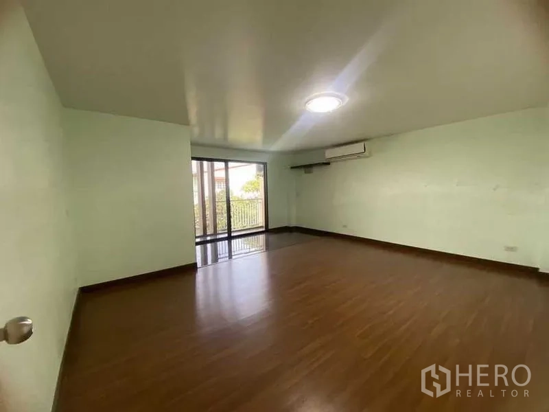 Home Office for rent in Don Mueang, Bangkok - Bright bedroom with wood floor, air conditioner and balcony access.