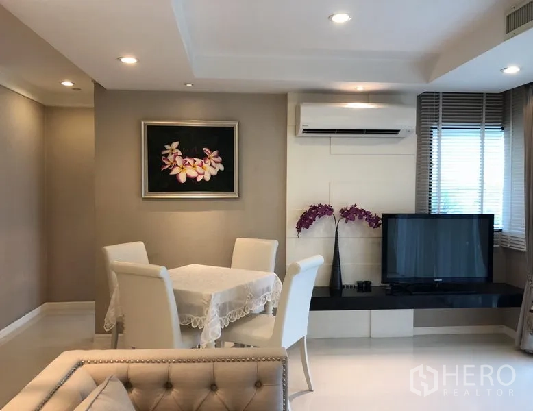 公寓 出租或出售在Sathon, Bangkok - 餐区挨着电视柜与壁挂空调，墙上花卉装饰画。