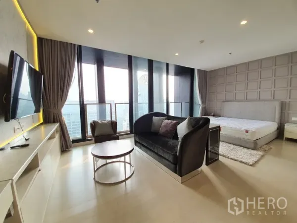 Condominium for rent in Pathum Wan, Bangkok - Spacious master bedroom with a sitting area, floor-to-ceiling windows and a skyline-view balcony.