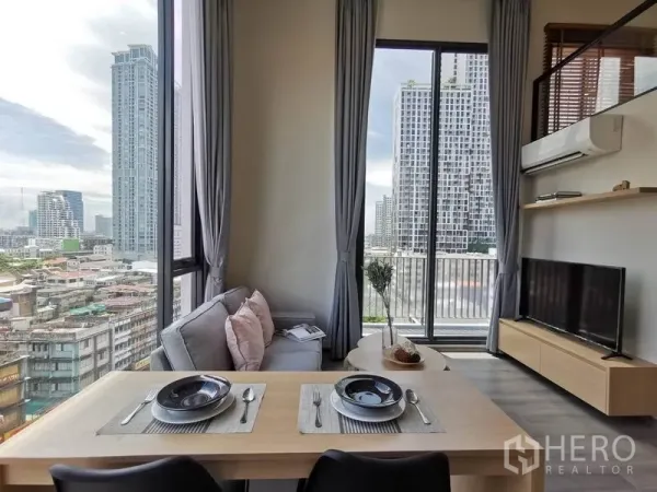 คอนโด ให้เช่าในPhaya Thai, Bangkok - โต๊ะทานอาหารและโซฟาหันสู่ทีวี พร้อมประตูกระจกสไลด์ออกระเบียงเห็นตึกสูง