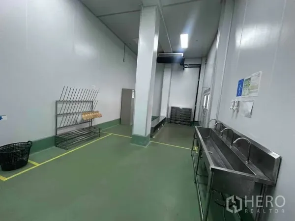 工厂 出租 - 卫生区配长不锈钢洗手槽、置物架与清晰地面标线。