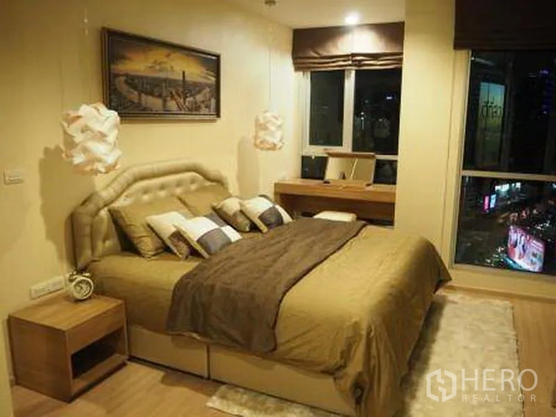 Condominium for rent in Sathon, Bangkok - Cozy Sathon condo bedroom with padded headboard, dressing desk and wide windows overlooking the city.
