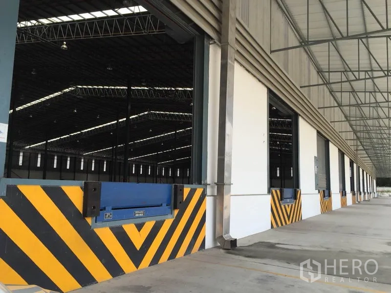 货栈 出租在Si Racha, Chon Buri - 装卸口的调节板与黄黑防撞条，连成一排的有顶月台。