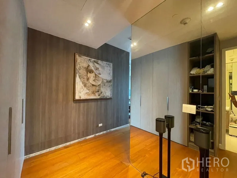 Condominium for rent in Pathum Wan, Bangkok - Spare room with mirrored wall, built-in wardrobes and wooden flooring.