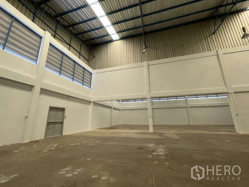 Factory for rent in Ban Phaeo, Samut Sakhon - Clear-span production floor with skylights, tall walls and an emergency door.