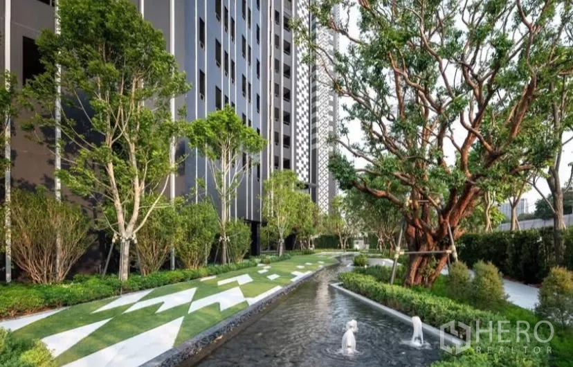 Condominium for rent in Chatuchak, Bangkok - Shaded garden with water feature and mature trees along the building.