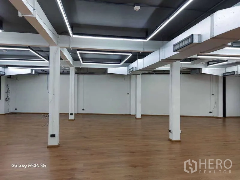 สำนักงาน ให้เช่าในKhlong Toei, Bangkok - ออฟฟิศโล่งกว้าง ไฟ LED กรอบสี่เหลี่ยมบนฝ้าสีเข้มและเสาค้ำ.