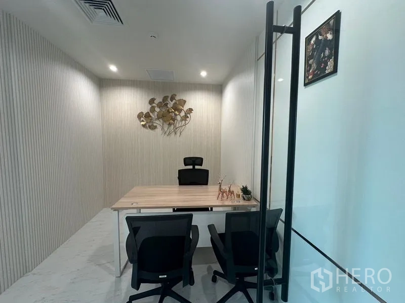 Office Space for rent - Minimalist private office behind glass door, wood desk and wall art.
