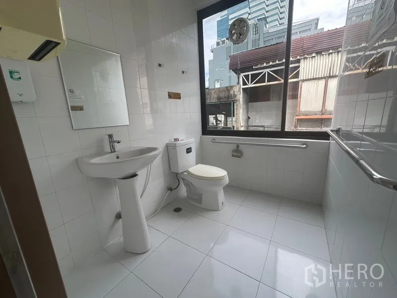 办公空间 出租在Bang Rak, Bangkok - 洁净瓷砖卫生间，配备洗手盆、坐便器、扶手和大窗。