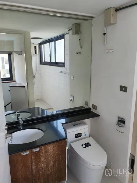 公寓 出售在Watthana, Bangkok - 卫生间配大镜子、黑色洗手台与坐便器。