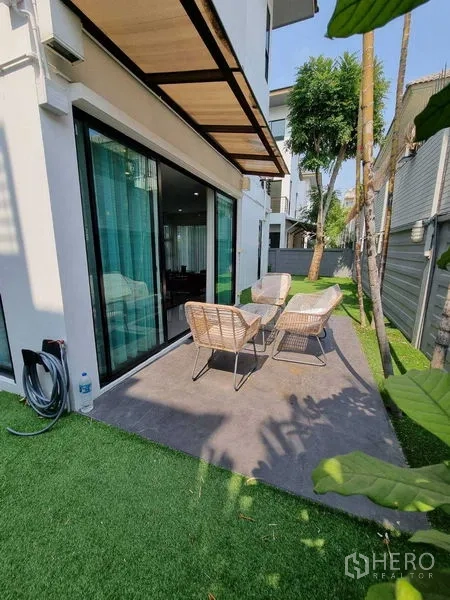 独立式住宅 出租或出售在Prawet, Bangkok - 侧院露台，户外桌椅与人造草坪，临推拉门。