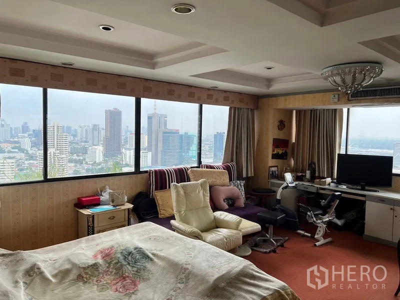 คอนโด ขายในKhlong Toei, Bangkok - ห้องนอนมาสเตอร์ หน้าต่างพาโนรามาเห็นวิวสกายไลน์กรุงเทพฯ พร้อมเก้าอี้พักผ่อนและโต๊ะทำงาน