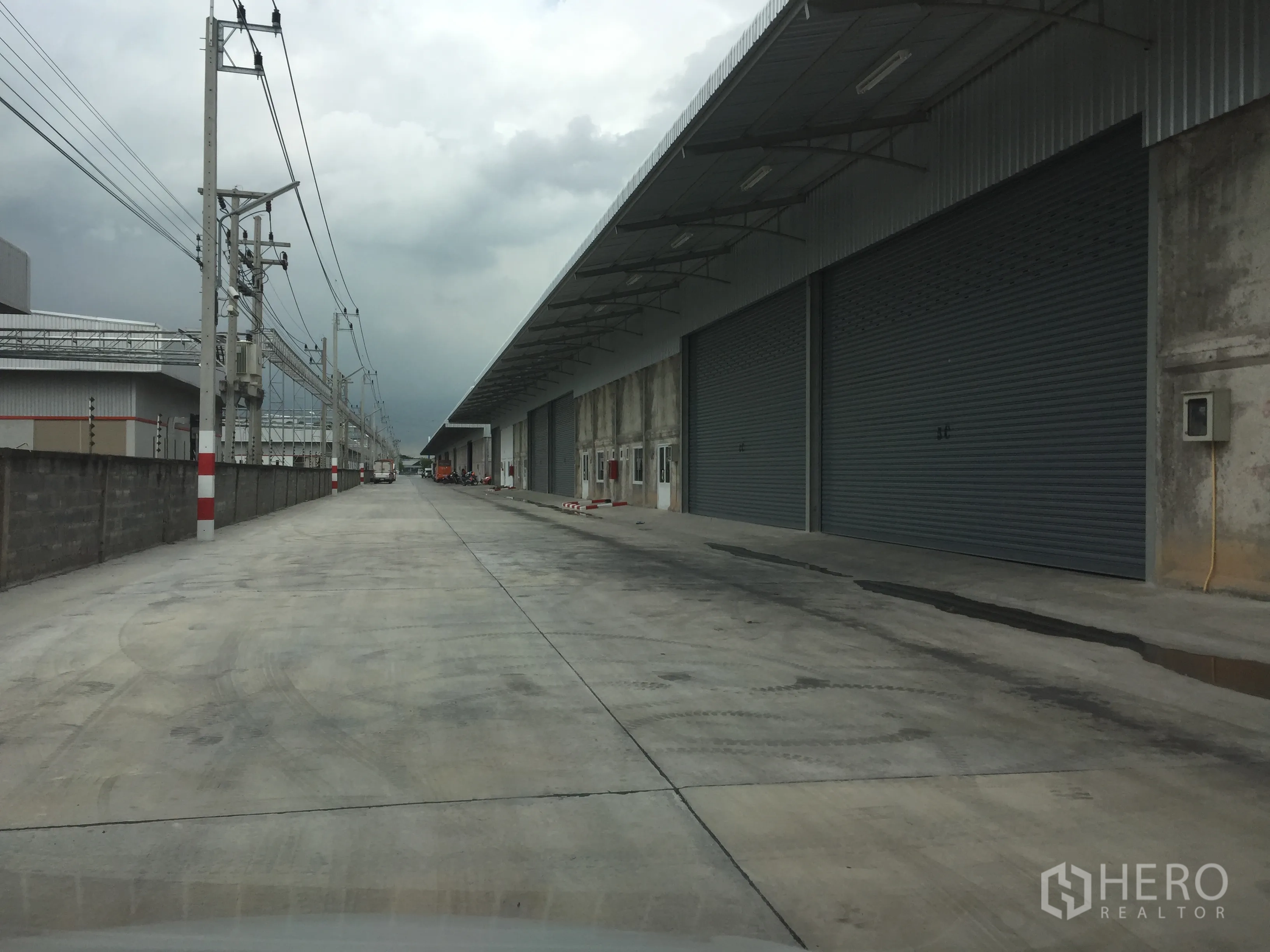 คลังสินค้า ให้เช่าในLam Luk Ka, Pathum Thani - ลานด้านนอกมีหลังคายาวและประตูม้วนขนาดใหญ่หลายบาน รองรับรถบรรทุก