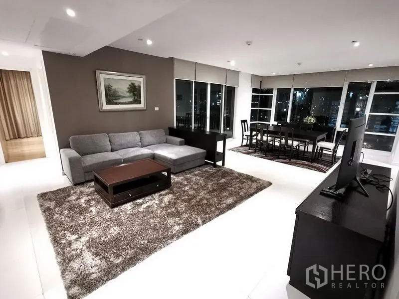 Condominium for rent in Watthana, Bangkok - Spacious open-plan living and dining room with city views, gray sectional sofa, and TV console.