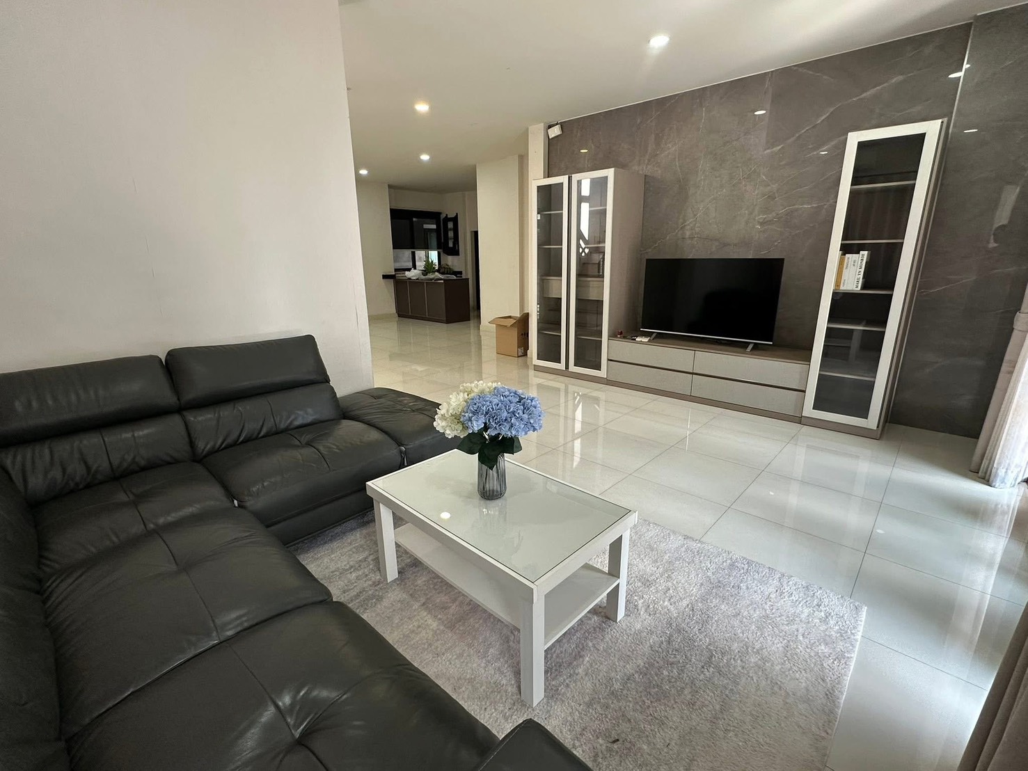 Detached House for rent in Bang Phli, Samut Prakan - Modern living room with black leather sectional, TV wall unit and glossy tile floors in a Bang Phli detached house.