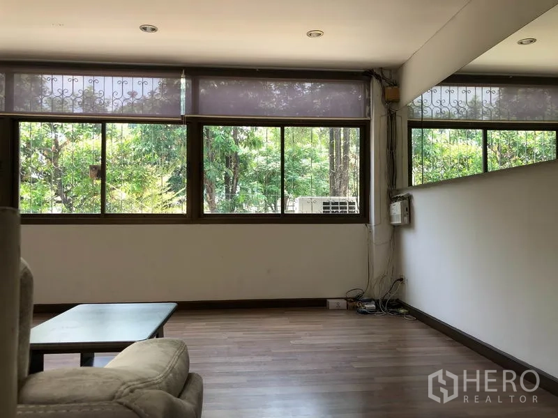 Warehouse for rent in Chatuchak, Bangkok - Lounge area with wide windows overlooking greenery and wood-style flooring.