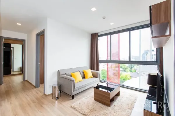 Condominium for rent in Watthana, Bangkok - Cozy living room with grey sofa, coffee table, large glazing and city views providing natural light.