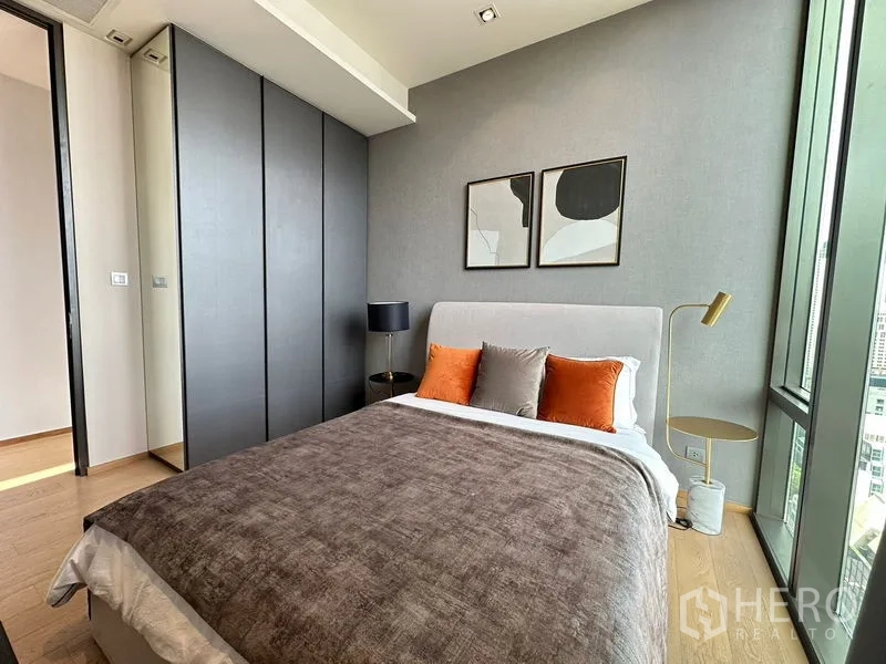 Condominium for rent in Pathum Wan, Bangkok - Second bedroom with built-in wardrobe, bedside lamps and full-height windows.