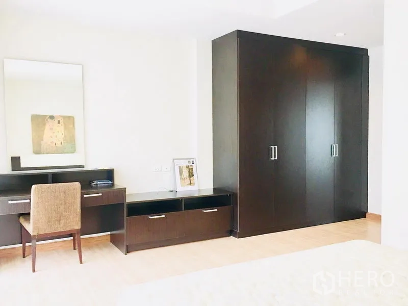 Townhouse for rent in Prawet, Bangkok - Bedroom corner featuring a dark wood wardrobe, dressing table, and chair.