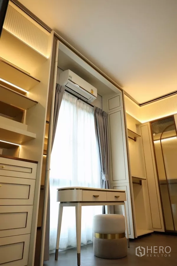 Detached House for rent or sale in Saphan Sung, Bangkok - Walk-in closet with built-in wardrobes, illuminated shelving, and vanity table.