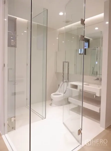 Condominium for sale in Watthana, Bangkok - Bright modern bathroom with frameless glass shower, white vanity and recessed lighting.