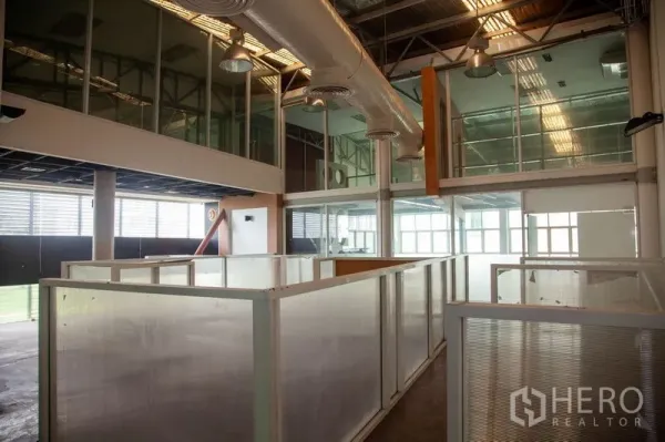 货栈 出租在Prawet, Bangkok - 曼谷帕威区仓库内景，挑高空间，玻璃夹层办公室、外露空调风管与分隔工位。