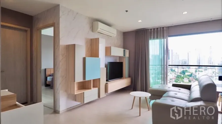 คอนโด ให้เช่าในKhlong Toei, Bangkok - ห้องนั่งเล่นสว่างพร้อมชั้นบิวต์อิน โซฟา ระเบียง และวิวสกายไลน์กรุงเทพฯ