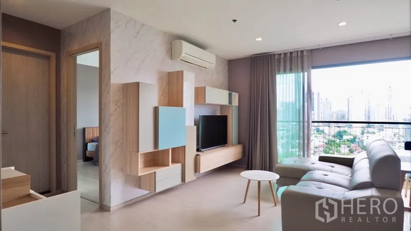 คอนโด ให้เช่าในKhlong Toei, Bangkok - ห้องนั่งเล่นสว่างพร้อมชั้นบิวต์อิน โซฟา ระเบียง และวิวสกายไลน์กรุงเทพฯ