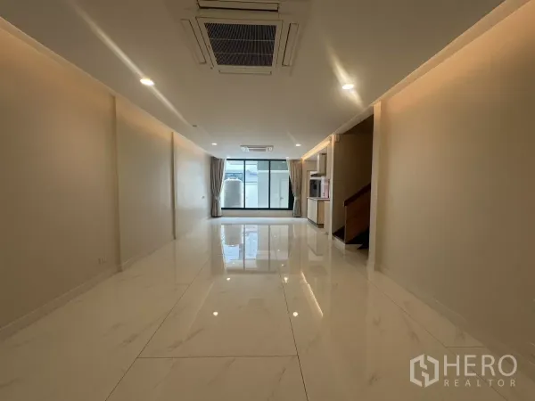Townhouse for rent in Watthana, Bangkok - Spacious open-plan living room with glossy marble-look floors and ceiling cassette AC.
