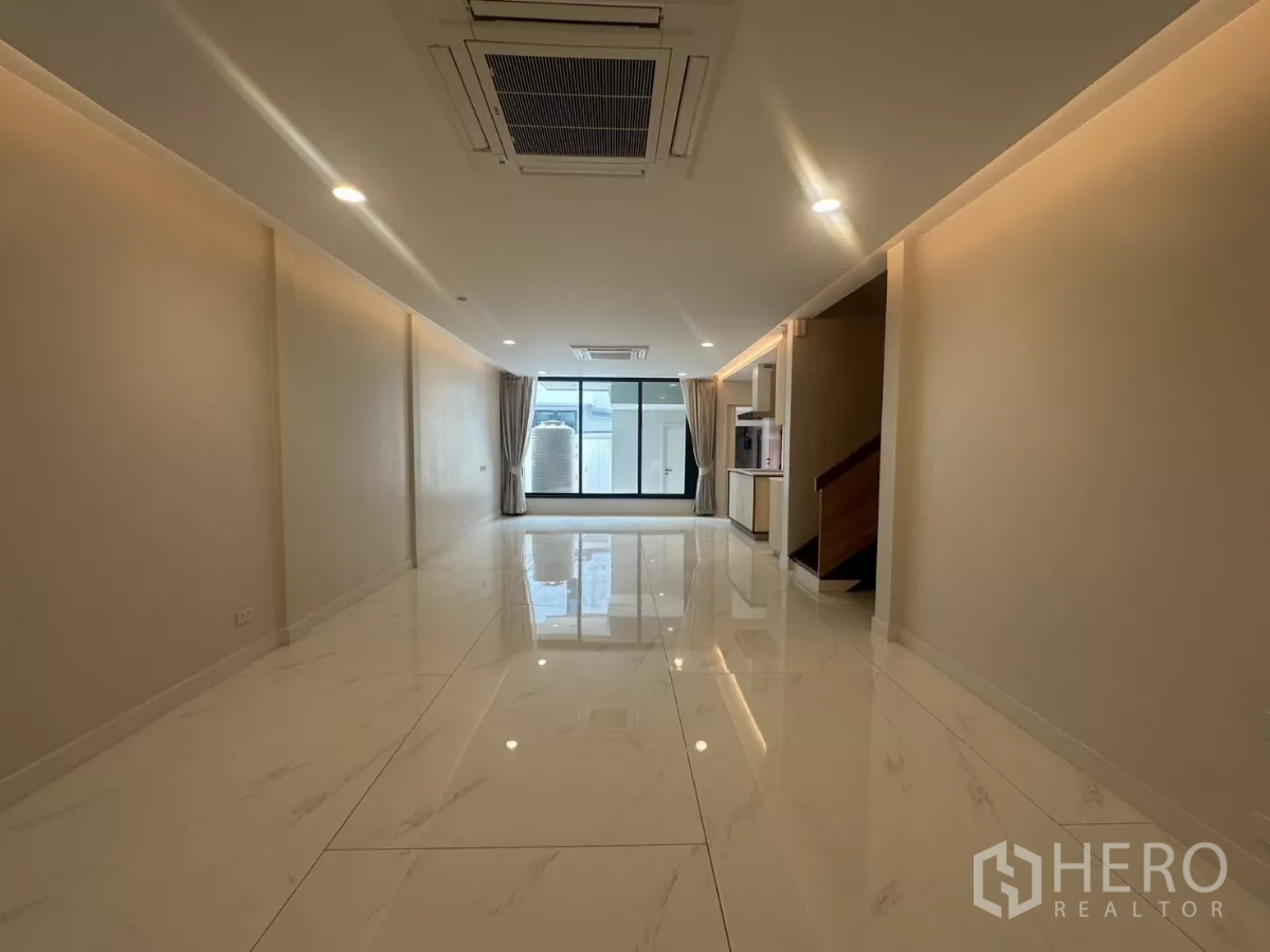 Townhouse for rent in Watthana, Bangkok - Spacious open-plan living room with glossy marble-look floors and ceiling cassette AC.