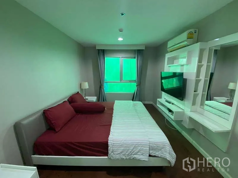 Condominium for  in Huai Khwang, Bangkok - Master bedroom with built‑in TV wall and shelving, bedside tables and window.