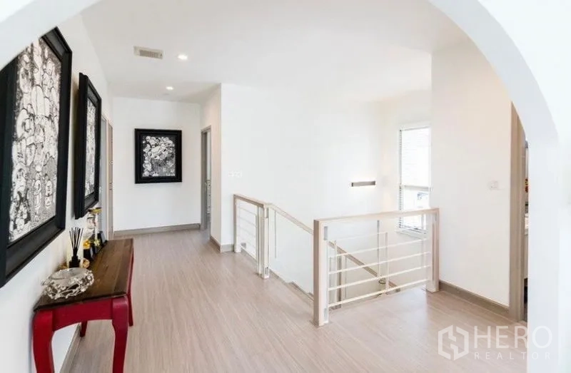 独立式住宅 出租 - 二层走廊，拱门入口、木地板、金属栏杆与装饰画。