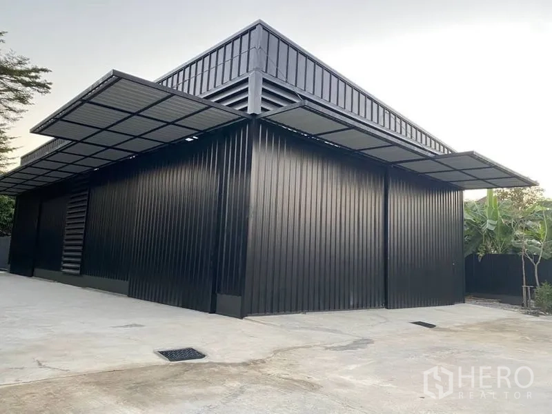 Warehouse for rent in Bang Kapi, Bangkok - Metal-clad warehouse exterior with wide entry doors, extended canopies, and a concrete driveway.