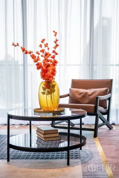 คอนโด ให้เช่าในKhlong Toei, Bangkok - โต๊ะกลางกระจกพร้อมแจกันสีอำพันและเก้าอี้พักผ่อนข้างหน้าต่างบานสูง